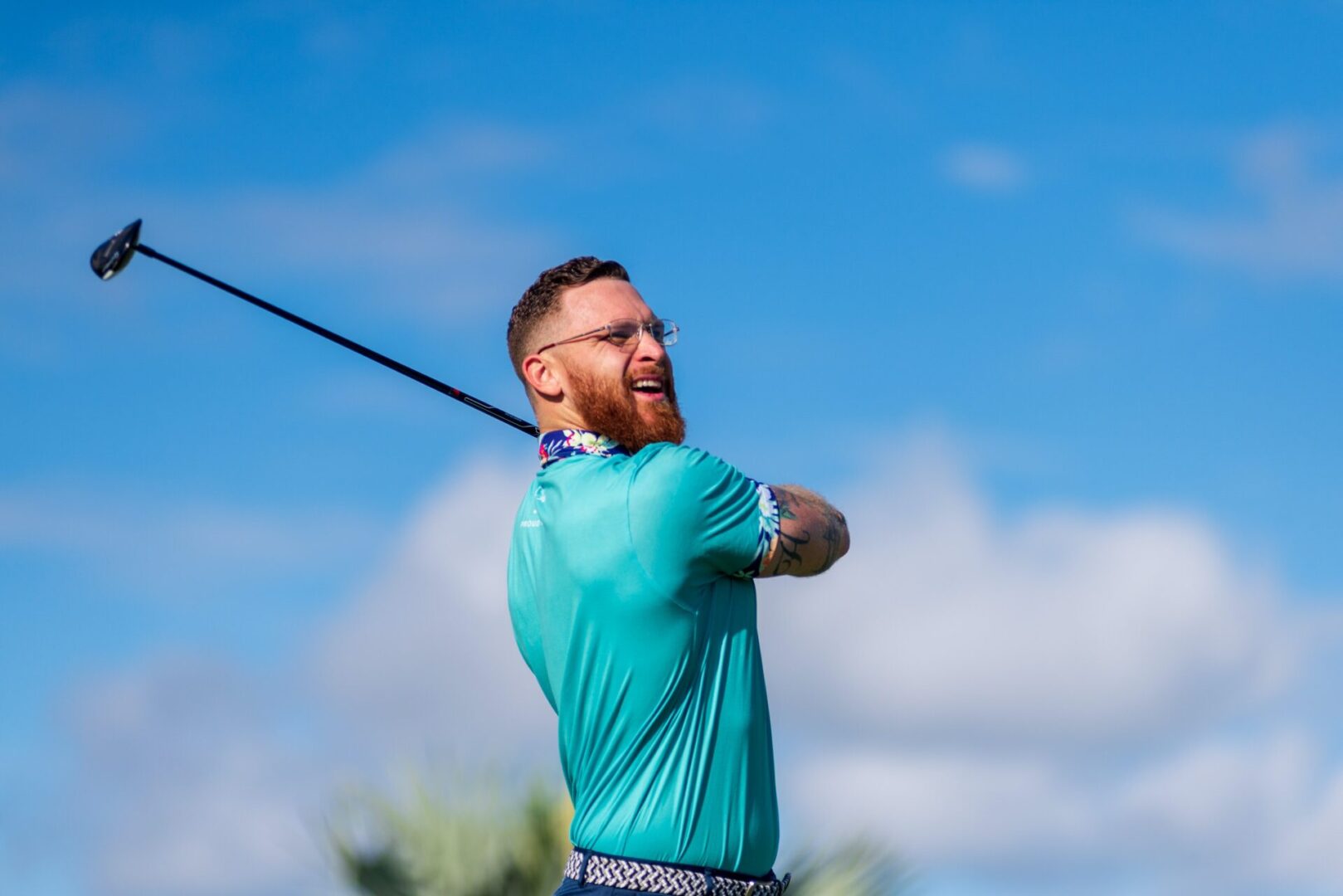 A man swinging at the sky with his golf club.